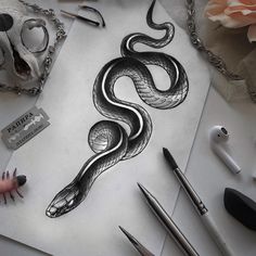 a drawing of a snake on paper next to pens and scissors