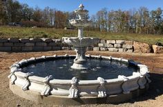 a stone fountain in the middle of a field