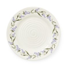 a white plate with blue flowers and green leaves on the rim, against a white background