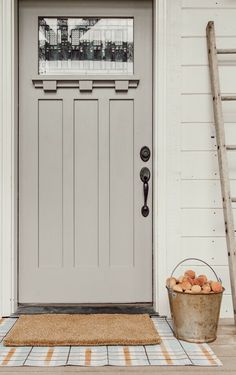 a bucket of apples sitting in front of a door with a ladder next to it