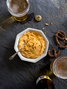 beer and pretzels are on the table next to each other, along with two glasses of beer