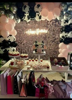 a table topped with lots of cakes and cupcakes next to balloons in the shape of panda's head