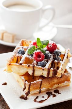 a waffle topped with berries and chocolate drizzled on top of it