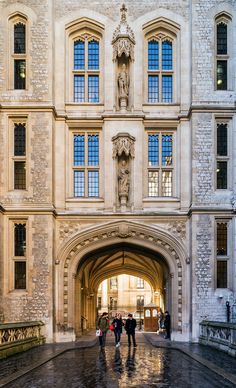 people walking under an archway in the middle of a large building with stone walls and arched doorways