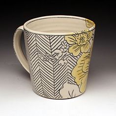 a white and yellow coffee cup with flowers on it