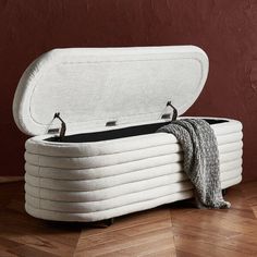 a large white bed sitting on top of a wooden floor next to a red wall