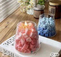 two candles sitting on top of a table next to each other with marshmallows in them