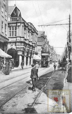 an old black and white photo of people walking down the street