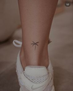 a woman's foot with a small palm tree tattoo on her left side ankle