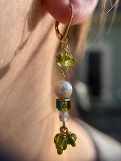 If you're looking for a little something to add some sparkle to your life, these dangle earrings are perfect. The delicate gold earrings are adorned with green crystal beads and faux pearls. They're stylish and chic, making them a great accessory for any modern woman. So if you're a nature lover or a June baby, these earrings are a must-have. Hypoallergenic earring hooks and rubber backs included. Green Crystal Drop Earrings With Dangling Beads, Elegant Green Beaded Drop Earrings, Green Pearl Charm Drop Earrings, Green Dangle Pearl Earrings, Green Pearl Dangle Earrings, Elegant Green Beaded Crystal Earrings, Green Dangle Pearl Earrings For Pierced Ears, Green Drop Earrings With Pearl Charm, Elegant Green Dangle Beaded Earrings