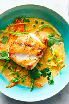 a blue bowl filled with fish and vegetables