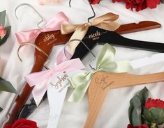 four personalized wooden hangers with bows and name tags on them next to flowers