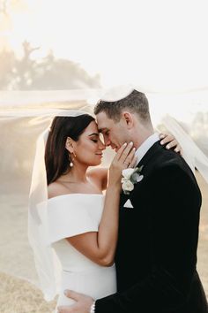 a bride and groom embracing each other in front of the sun shining through the veil