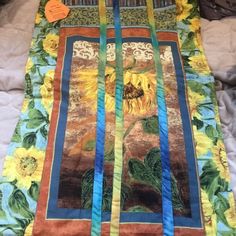 a quilt with sunflowers on it laying on a bed