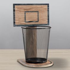 a trash can with a basketball hoop in it sitting on top of a wooden table