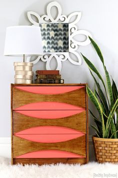 a wooden dresser sitting next to a potted plant on top of a white rug