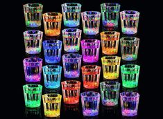 many different colored glasses sitting next to each other on a black surface with the lights turned on