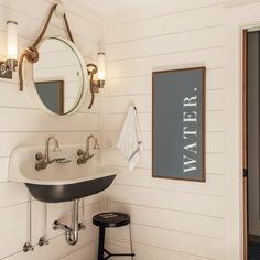 a bathroom with a sink, mirror and stool next to a door that says water