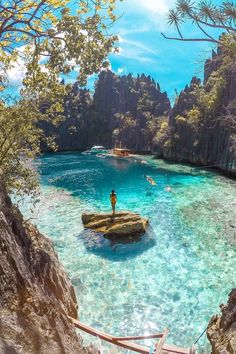 a man standing on a rock in the middle of a river with clear blue water