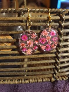 two pink flowers are hanging from glass earrings