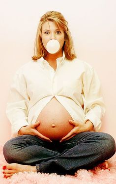 a pregnant woman is sitting on the floor with her pacifier in front of her mouth