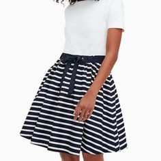 a woman wearing a white shirt and black and white striped skirt with a blue belt