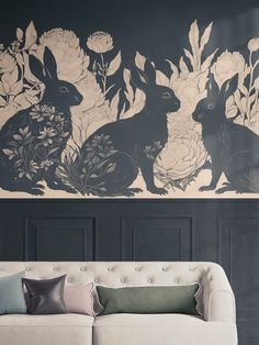 a living room with a couch and wallpaper on the walls that has rabbits sitting in front of flowers