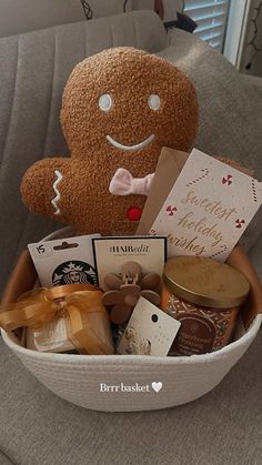 a stuffed teddy bear sitting in a basket filled with treats and cards on a couch