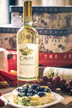 a bottle of cavit sits on a plate next to some grapes and cheese