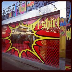 a store front with red and yellow graffiti on it's glass window displays the word pop - art