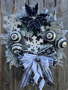 a wreath with snowflakes and ornaments hanging on the side of a wooden fence