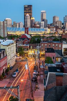 the city skyline is lit up at night, with buildings in the foreground and street lights on either side