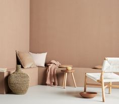 a room with two chairs, a table and a vase on the floor in front of a wall