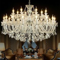 a chandelier hanging from the ceiling in a living room with chairs and tables