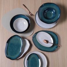 a table topped with plates and bowls on top of a wooden table next to utensils