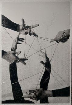 four hands reaching through strings to reach something