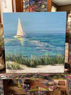 an easel with a painting of a sailboat in the ocean