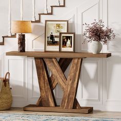 a wooden table with two pictures on it next to a stair case and potted plant