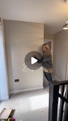 a woman standing on top of a stair case next to a wall in a room