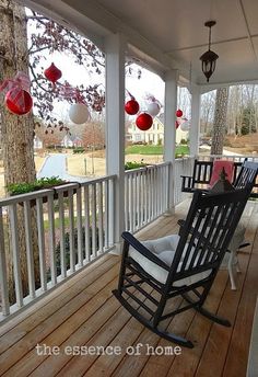 a porch with rocking chairs and lanterns hanging from it's ceiling over the deck