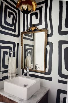 a white sink sitting under a bathroom mirror next to a wall mounted faucet