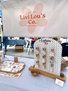 a table topped with lots of earrings and jewelry next to a sign that says livlilou's co