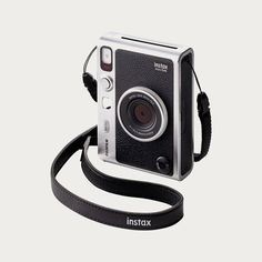 an instax camera with a black strap attached to it's front and side