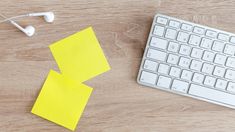 two sticky notes sitting on top of a wooden desk next to a keyboard and headphones