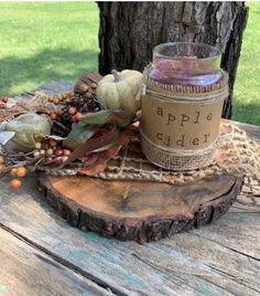 an apple cider jar sitting on top of a wooden table next to a tree