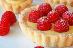 small cupcakes with white frosting and raspberries on top