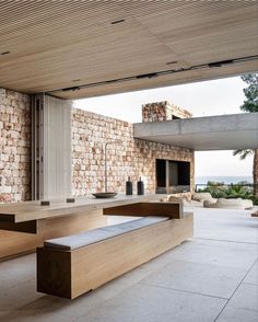 a bench sitting in the middle of a room next to a stone wall and window