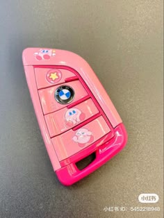 a pink cell phone with hello kitty stickers on the front and back sides, sitting on a gray surface