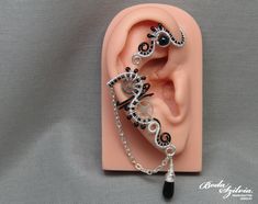 Steampunk ear wrap in silver and black color, decorated with black onyx. No piercing required! It's made of black artistic and nickel free silver plated wire, silver plated chain, seed beads, a black onyx gemstone, a matching black glass drop shaped bead and recycled stainless steel watch wheels. Available: - left ear - right ear  - pair Made for order. I'll need 1-5 days to make your ear cuff. Please note that each one is made 100% by hand and may vary a little from the photo. You can find more Handmade Black Ear Cuff Gift, Handmade Black Ear Cuff As Gift, Handmade Black Ear Cuff For Gift, Black Steampunk, Felt Pouch, Wrap Earrings, Steampunk Jewelry, Cuff Earrings, Stainless Steel Watch