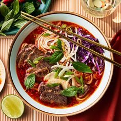 a bowl of beef and cabbage soup with chopsticks on the table next to it